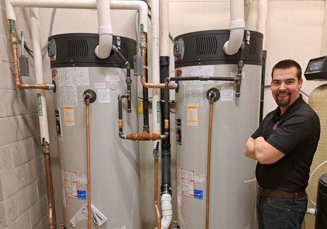 Technician installing a new residential water heater in a wisconsin utility room
