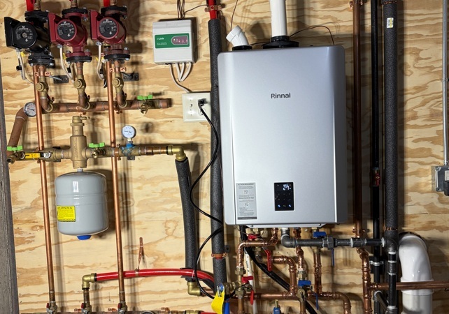 Plumbing technician repairing a faulty water heater with tools beside the tank in wisconsin